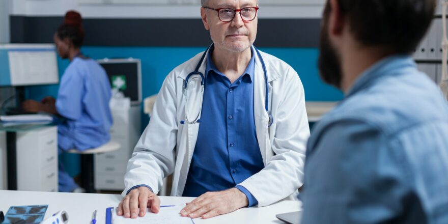 Doctor doing medical consultation with patient in cabinet