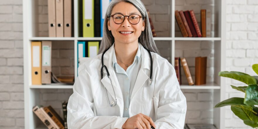 Happy middle-aged woman doctor sitting at the desk