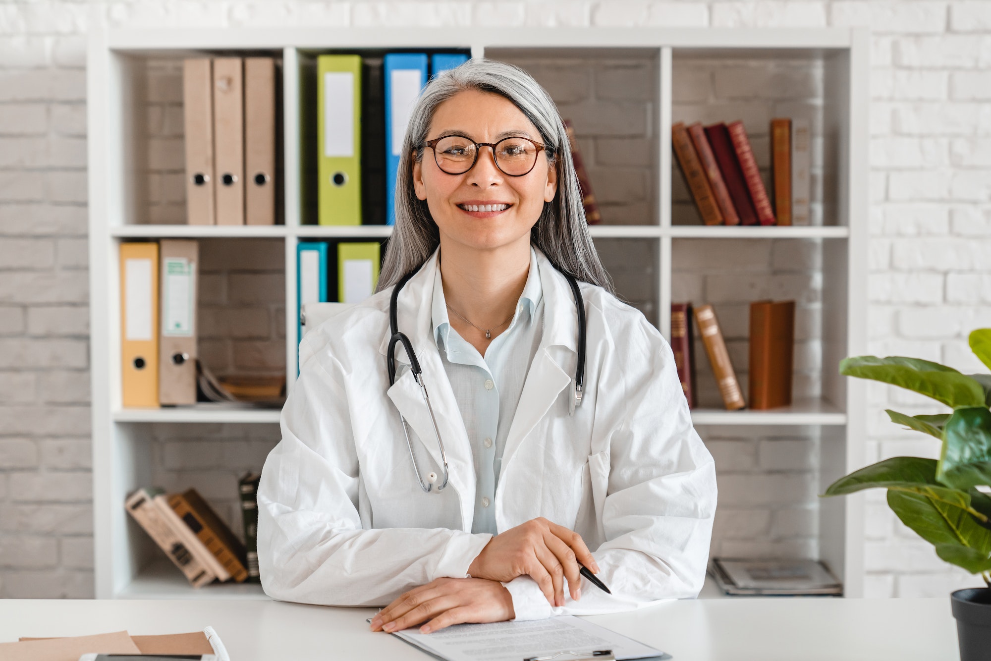 Happy middle-aged woman doctor sitting at the desk
